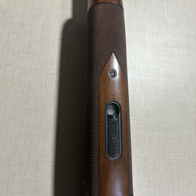 Parte superior de arma de fogo em madeira e metal com padrão gravado