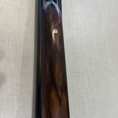 Espingarda com canos pretos e coronha de madeira trabalhada