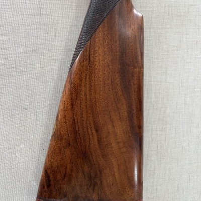 Corpo de madeira polida castanha com textura quadriculada preta e borracha preta com detalhes vermelhos