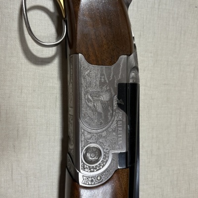Espingarda Beretta com madeira escura e detalhes gravados em metal