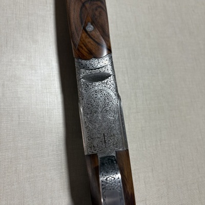 Espingarda com madeira castanha gravada e detalhes metálicos prateados com padrão floral