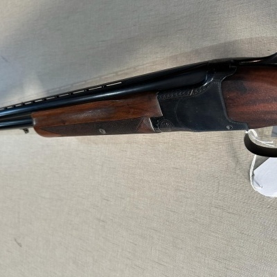 Espingarda de canos duplos com coronha de madeira e etiqueta branca pendurada