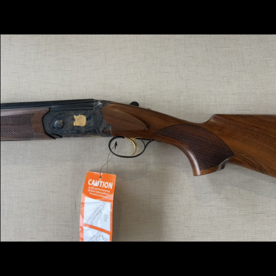 Espingarda de caça com coronha de madeira e etiqueta de aviso laranja