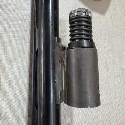 Parte de arma metálica com mola em fundo bege