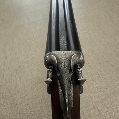 Espingarda de canos duplos com cabo de madeira e detalhes metálicos gravados