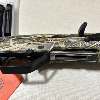 Espingarda Beretta camuflada em tons de verde e bege com detalhes pretos e texto BERETTA.