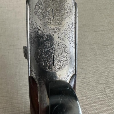 Mecanismo metálico gravado floral e punho de arma em madeira escura