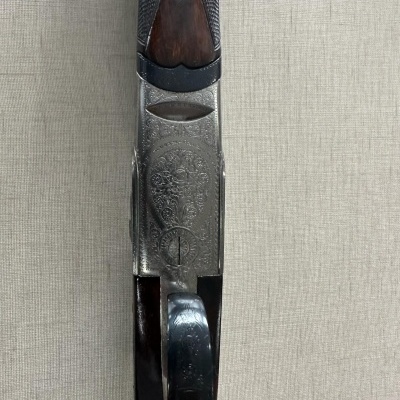 Parte inferior de espingarda com madeira castanha e metal prateado com gravações