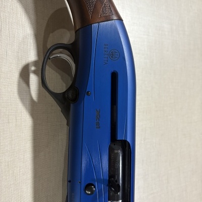Espingarda azul Beretta com punho em madeira castanha e gatilho prateado