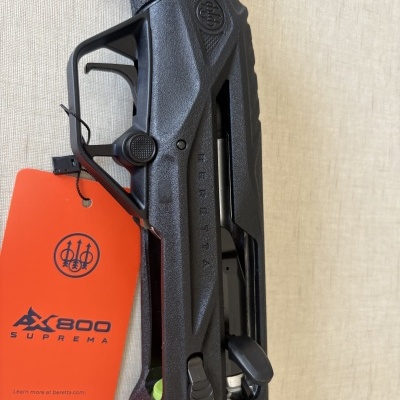 Parte preta de uma arma com etiqueta laranja AX800 SUPREMA e selo BERETTA