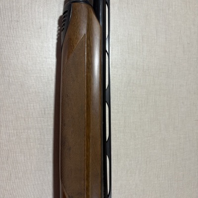 Parte de coronha de arma de fogo com madeira castanha e tubo metálico preto