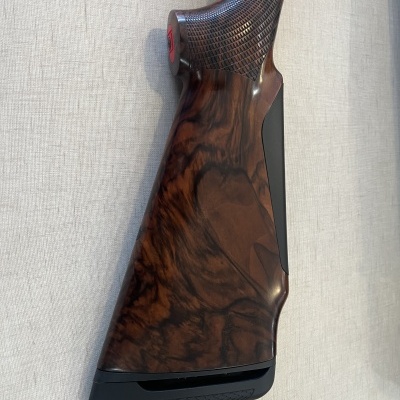 coronha de espingarda em madeira escura com textura quadriculada na pega e almofada preta