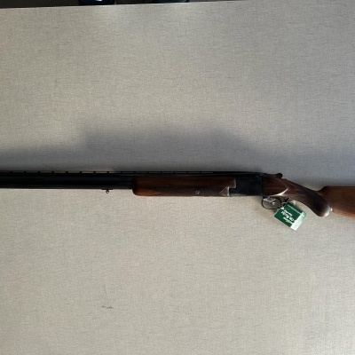 Espingarda de cano duplo com coronha de madeira castanha sobre superfície cinzenta