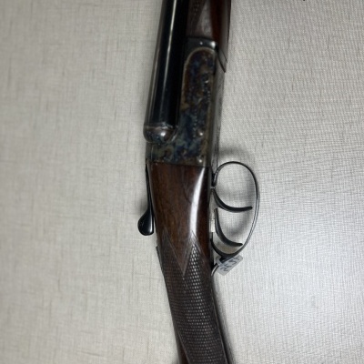 Espingarda de canos duplos em madeira e metal sobre superfície clara