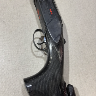 Espingarda Beretta 686 com detalhes em vermelho e madeira escura sobre fundo claro