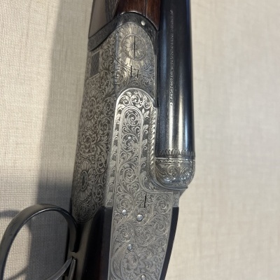 Close-up de espingarda com metal gravado e punho de madeira escura