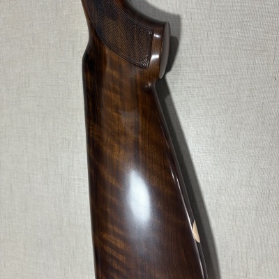 Empunhadura de madeira castanha com relevo e ponta vermelha numa superfície bege