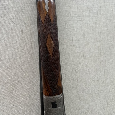 Espingarda de cano duplo com coronha em madeira trabalhada e acabamento metálico