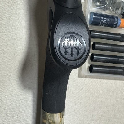 Punho de arma Beretta preto e camuflado com acessórios e óleo para armas.