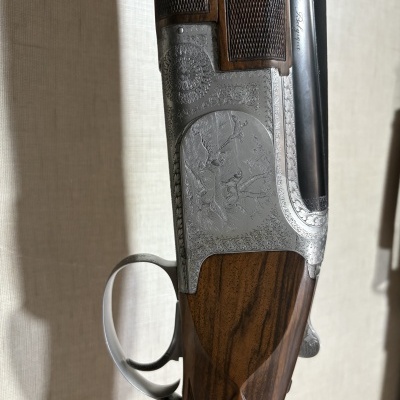 Espingarda de caça com gravações em metal prateado e madeira escura