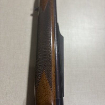 Parte superior de uma arma de fogo com madeira castanha e metal preto