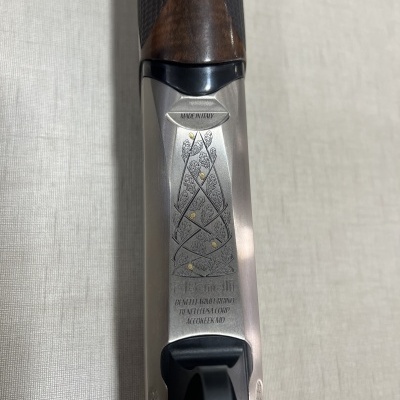 Parte superior de arma com gravações metálicas e empunhadura em madeira