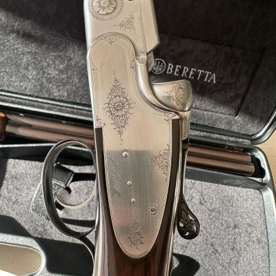 Arma de fogo Beretta decorada com metal prateado e madeira, dentro de mala acolchoada preta com logo Beretta