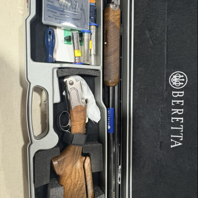 Estojo cinza com espingarda Beretta desmontada e acessórios.