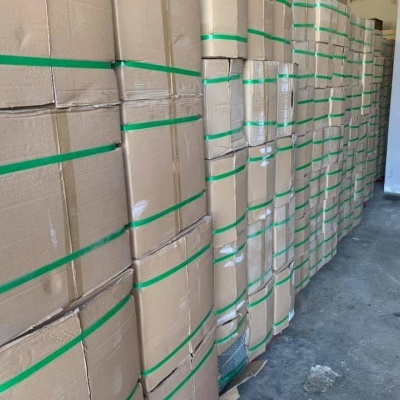 Caixas de cartão empilhadas com cintas verdes num armazém