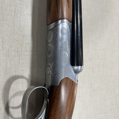 Espingarda com coronha em madeira castanha e cano preto com detalhes ornamentais em metal prateado
