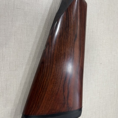 Cabo de arma em madeira castanha com base preta sobre fundo claro