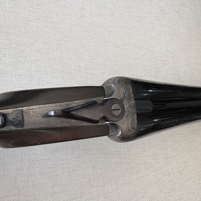Parte de espingarda com detalhes em metal gravado e madeira escura