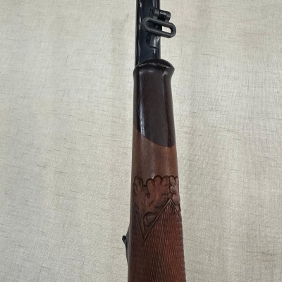 Espingarda com cano preto e coronha em madeira castanha gravada