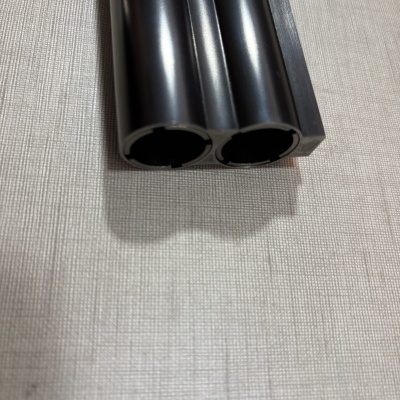 Extremidade de tubos pretos em suporte preto sobre superfície clara