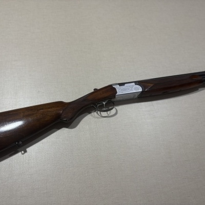Espingarda de caça em madeira e metal sobre superfície cinzenta