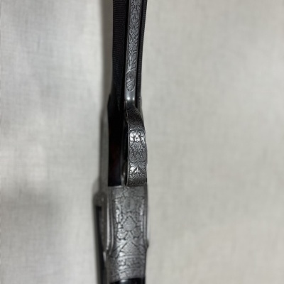 Detalhe de arma de fogo com gravações em metal e madeira escura