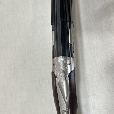 Espingarda de canos duplos em metal prateado com gravações decorativas e madeira escura