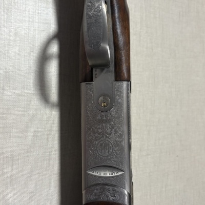 Arma de fogo com punho em madeira escura e parte metálica gravada com padrões e texto