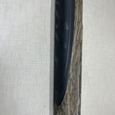 Cano de arma camuflado com empunhadura preta e texto 