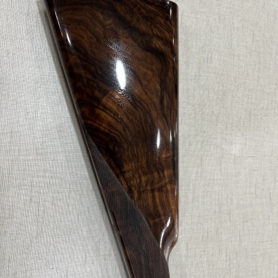 Mira de arma de fogo em madeira polida sobre tecido cinza claro