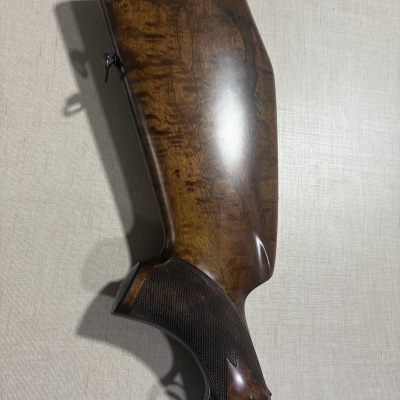 Coronha de arma em madeira castanha com detalhes metálicos e textura no punho