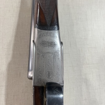 Espingarda com madeira e metal prateado sobre tecido claro