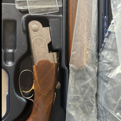 Arma de fogo Beretta com punho em madeira numa caixa preta com componentes embalados em plástico