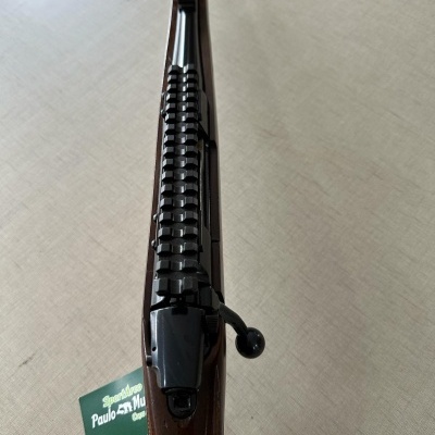 Espingarda com coronha de madeira e acabamento em metal sobre superfície clara