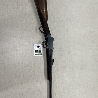 Espingarda com coronha de madeira e cano metálico pendurada em parede