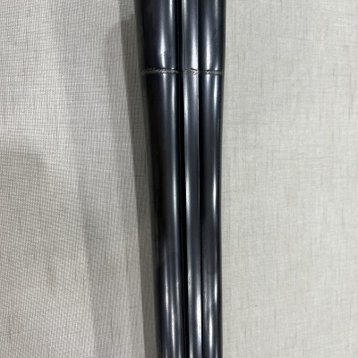 Túnicas longas pretas com textura lisa sobre tecido cinza claro.