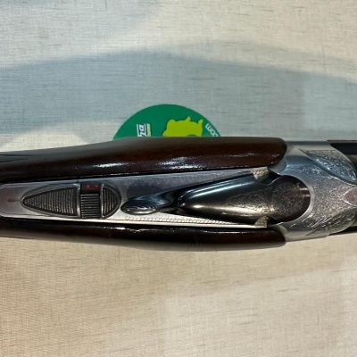 Espingarda de cano duplo com acabamento metálico e madeira escura sobre tecido branco