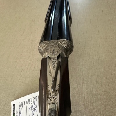 Arma de cano duplo com madeira escura e detalhes metálicos ornamentais