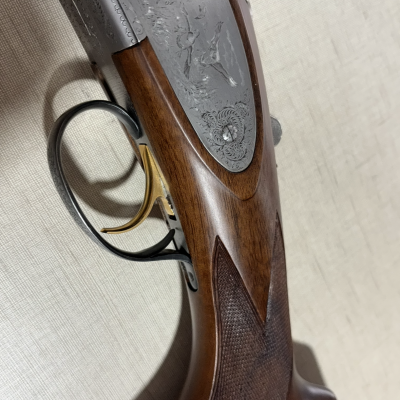 Espingarda de caça com coronha em madeira castanha e detalhes metálicos gravados