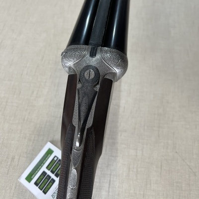 Espingarda de canos pretos com gravações e punho em madeira